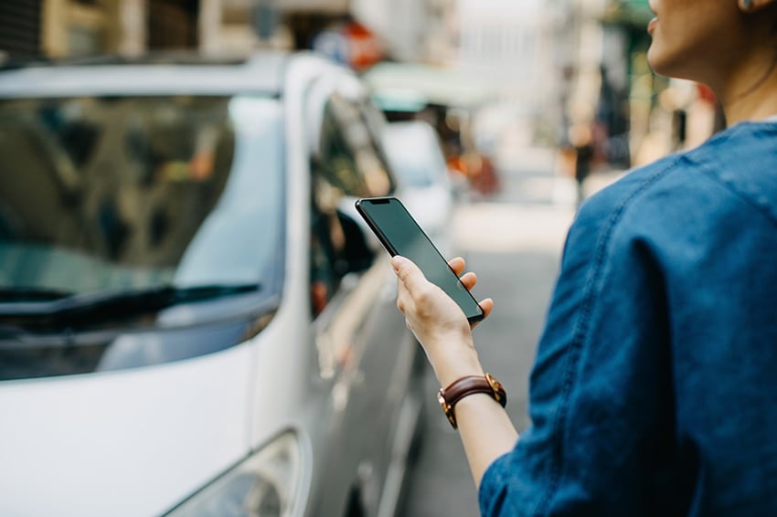 Mujer mirando un coche en el teléfono